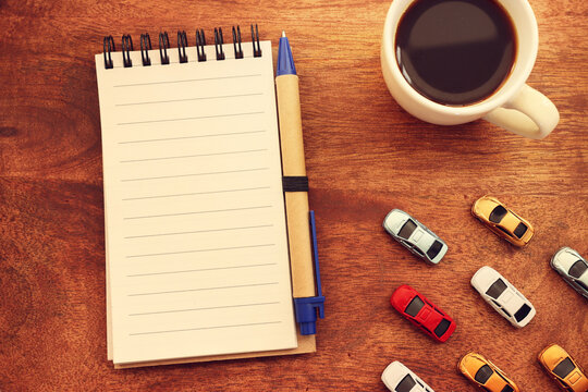 Concept image of empty notebook on a wooden table with small toy cars