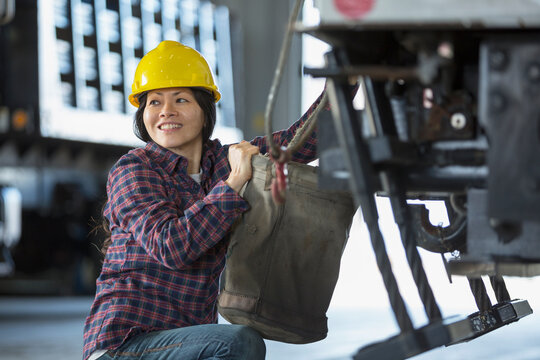 Female power engineer attaching canvas bucket to equipment truck