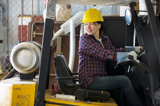 Female power engineer driving a forklift truck in service garage