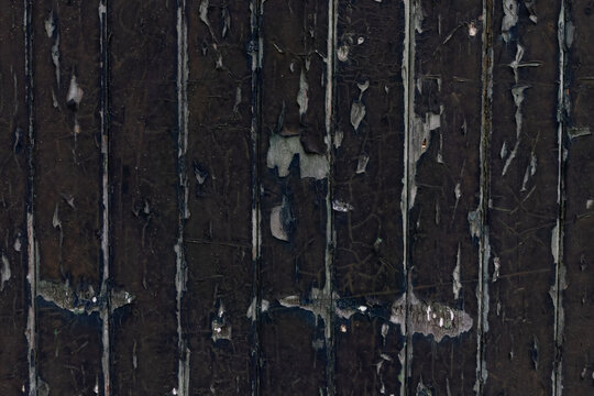 Texture of old vertical weathered wooden planks with cracked and peeling dark paint as background