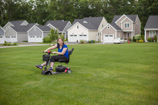 Young Woman with Cerebral Palsy riding her scooter on her lawn