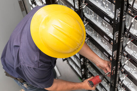Engineer connecting energy storage batteries for back up power to an electric power plant
