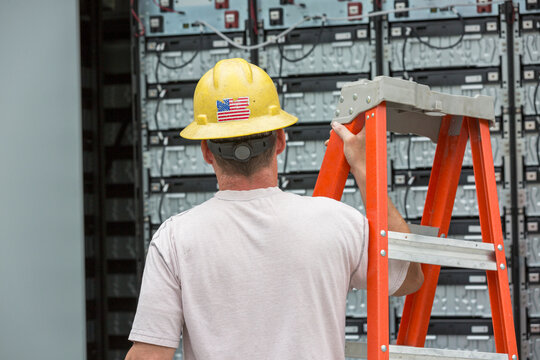 Engineer connecting energy storage batteries for back up power to an electric power plant