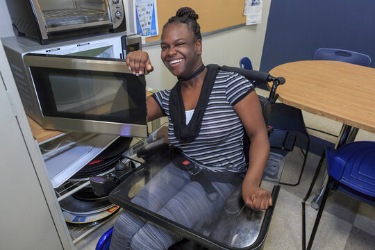 Teen with Cerebral Palsy using oven in the kitchen
