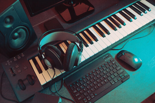 Estudio de m&uacute;sica iluminado en rojo con teclado, auriculares y altavoces. Montaje dram&aacute;tico de estudio de m&uacute;sica con luz roja; espacio de trabajo de producci&oacute;n con un ambiente &iacute;ntimo para la industria