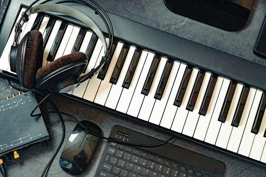 Auriculares sobre teclado de piano con rat&oacute;n de ordenador, estudio. Auriculares apoyados sobre las teclas del piano con rat&oacute;n; configuraci&oacute;n de estudio casero y de producci&oacute;n musical para uso editoria