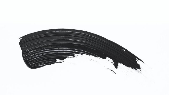 Close up of curved black mascara brush stroke isolated on white background. Macro shot of wand with mascara texture smudge swatch