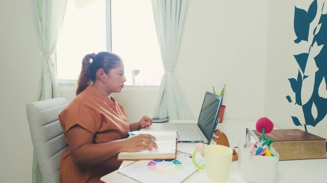 Focused hispanic woman working remotely from her home office desk