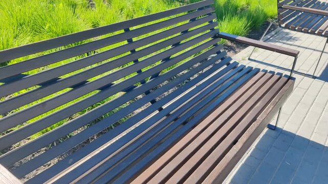Empty wooden park bench with special sign for elderly people and low mobility citizens, standing near green grass, representing social care and accessible urban environment.