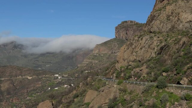 Lonely vehicle driving along winding mountain cliff road