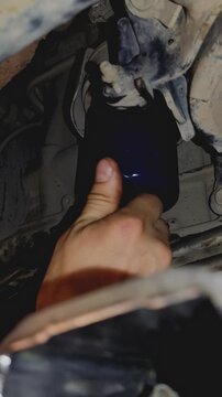 A bare hand unscrewing a blue spin-on car oil filter