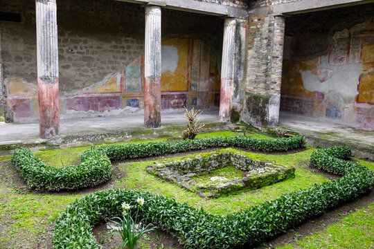 The House of the Vettii in Pompeii, Italy, features a peristyle garden with manicured hedges, a central impluvium, and ancient frescoes on the surrounding walls.