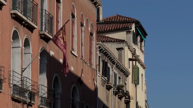 Slow motion dark red flag waving on classic European facade