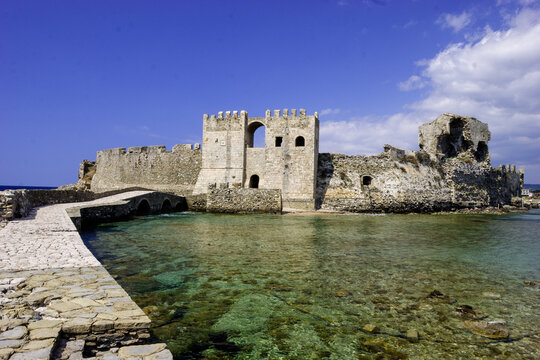 Methoni Castle, Greece, on a sunny day with clear blue skies and calm turquoise waters.