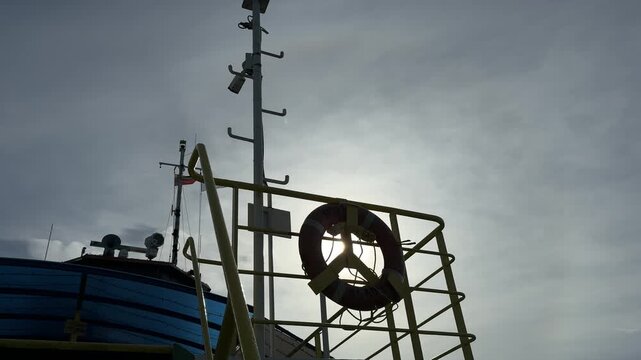 Backlit lifebuoy and mast on ferry deck