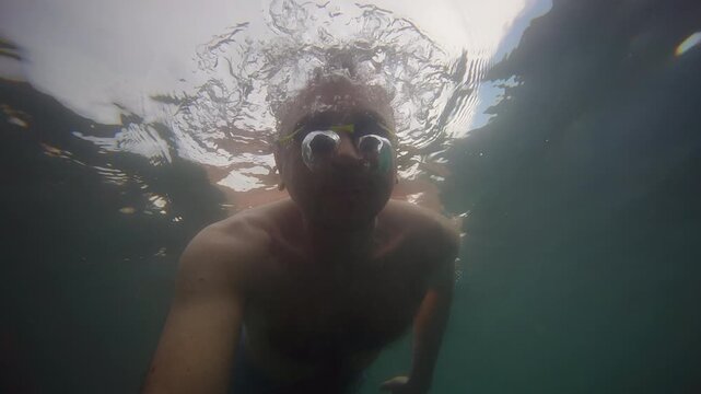 Dynamic underwater point of view footage of a swimmer moving through clear sea water