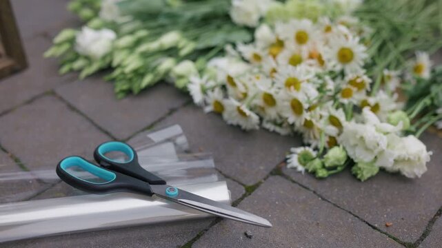 Florist tools and fresh chamomile flowers on a stone pavement workspace