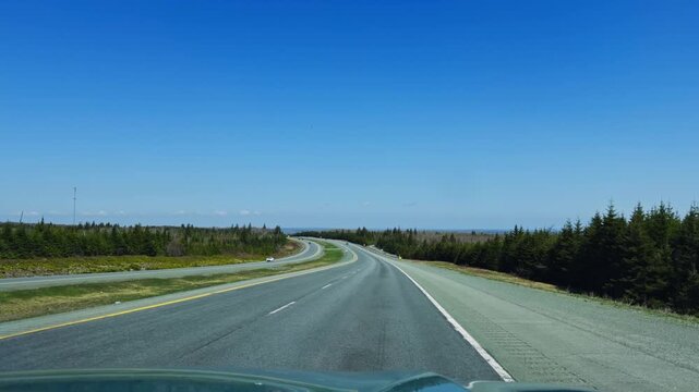 Immerse yourself in the serene drive through Nova Scotia, Canada, as you travel on open roads surrounded by lush greenery and clear blue skies