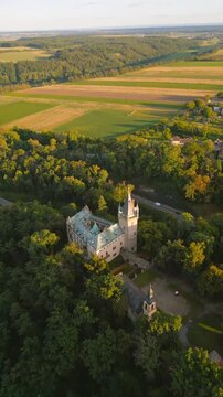 Stranov Castle sits in the countryside with green fields and trees surrounding it. The landscape shows bright fields under a clear sky. Visitors enjoy views of this historic site.