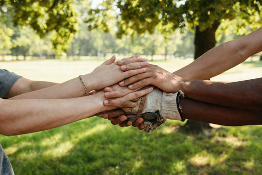 Close-up of diverse hands stacked together symbolizing unity and teamwork outdoors
