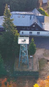 Explore the Slovanka lookout tower in the Jizera Mountains surrounded by vibrant autumn colors. Experience breathtaking aerial views of this historic metal structure and the lush forest.