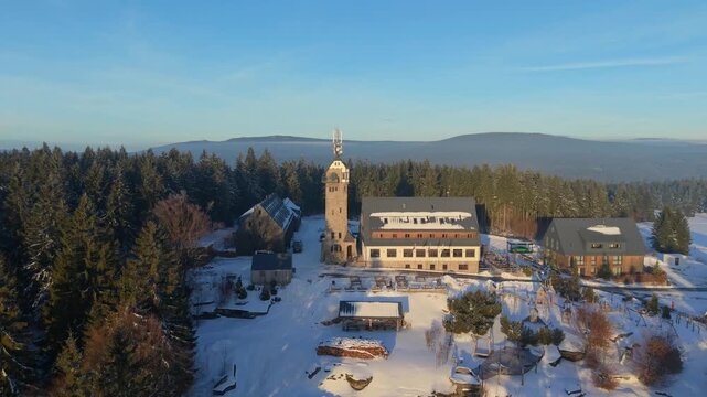 View the Kralovka lookout tower in the Jizera Mountains during winter. See the tower and surrounding area covered in snow. Enjoy the view from the elevated spot in winter landscape.