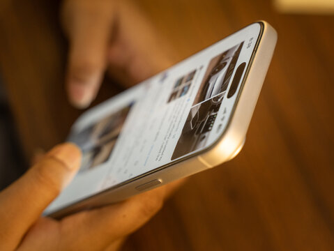 Close-up of a hand scrolling through a social media feed on a smartphone, depicting digital addiction, mindless browsing, and screen dependency in daily life.
