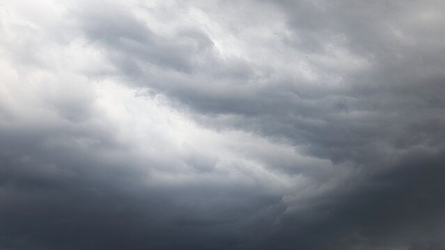 Dramatic storm cloudscape: dark thunderclouds roll across a gray sky