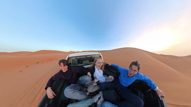 Friends Riding in Pickup Bed Across Golden Sand Dunes