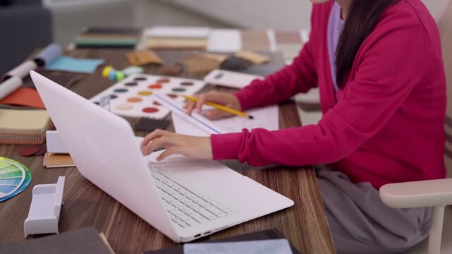 interior designer working with color palette material samples laptop computer planning furniture design project creative workspace office studio environment