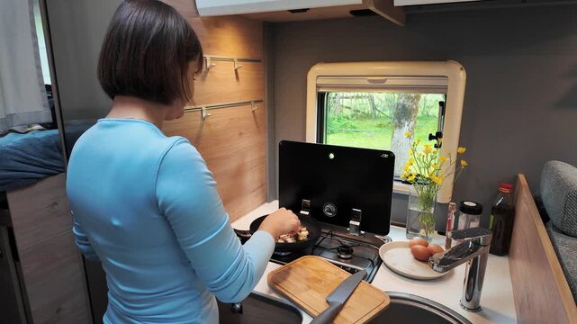 Batumi, Adjara, Georgia - 02.05.2026: Woman Cooking Breakfast Inside Camper Van Kitchen. Van Life Food Preparation.