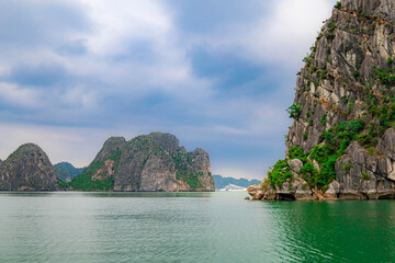 Naklejka premium Beautiful tropical view of Halong bay with turquoise sea, rocky cliffs, and lush green landscape in Vietnam.