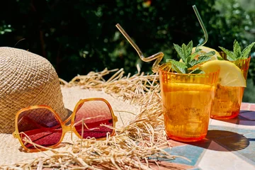 Summer refreshing lemonade drink or non alcoholic cocktail with lemon slices in orange drinking glasses on the table in the garden. Fresh healthy cold lemon beverage. Water with lemon. Summer mood. © Caterina Trimarchi