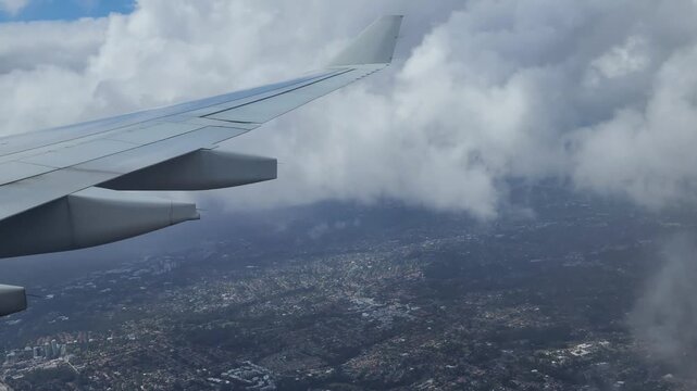 Sydney, Australia - Airplane wing view above city and clouds during flight, showcasing aerial travel perspective with urban landscape, sky scenery and in‑flight atmosphere. 