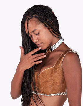 Young black woman with braided hair wearing traditional African animal hide top and beaded necklace