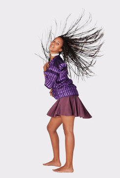 Young african woman flipping braided hair in traditional purple pattern shirt and skirt