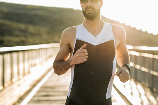 Runner trains on a bridge at sunset while sprinting