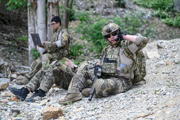 Fototapeta premium Special forces soldiers in tactical gear resting and communicating in a wooded area