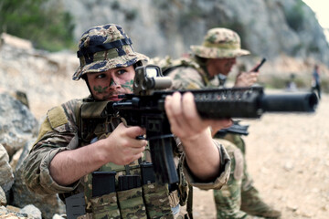 Fototapeta premium Soldier with camouflage face paint aims rifle during tactical training exercise