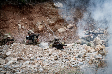 Obraz premium Special forces soldiers in camouflage take cover behind rocks during a tactical operation