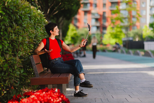 Solo female traveler vlogging with smartphone on a city bench