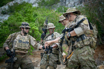 Obraz premium Soldiers in camouflage gear huddle together in a forest, sharing a moment of unity