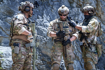 Fototapeta premium Special forces soldiers in tactical gear with rifles in a rocky, arid environment