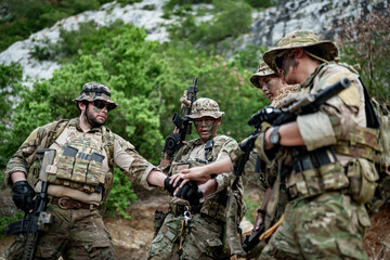 Fototapeta premium Military team in camouflage gear huddles together in a forest setting