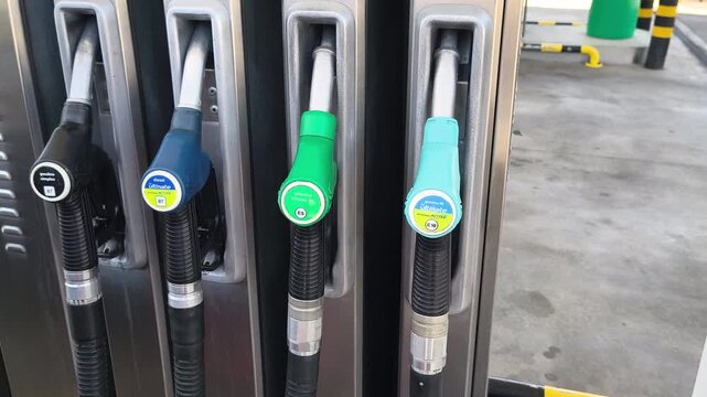 Hand selects a gasoline nozzle at a fuel station pump preparing for vehicle refueling illustrating fuel choice transportation energy supply and everyday automotive service