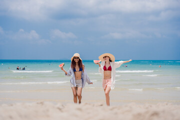 Naklejka premium Summer beach friendship concept. Two happy women in swimwear enjoying fresh watermelon on tropical beach, celebrating vacation freedom and sunny holiday moments. summer, women, vacation, friendship