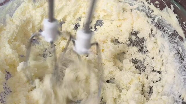 Electric mixer whips smooth buttercream frosting into a light fluffy texture creating creamy dessert filling for cake decorating baking and pastry preparation