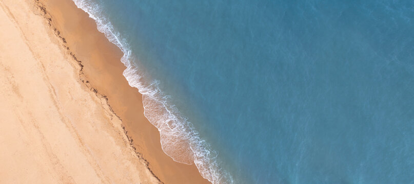 Tropical beach landscape from drone perspective showing turquoise sea and smooth sand coastline. Minimal natural background ideal for travel websites, resort promotions, and summer design projects.
