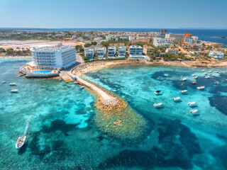 Obraz premium Aerial view of resort in Mallorca, Balearic Island, Spain. Top view of turquoise sea water, hotel on the beach, boats and yachts anchor in bay, stone pier on sunny summer day. Coastal drone landscape