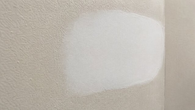 Close-up of a repaired wall showing texture difference between old and new patch.